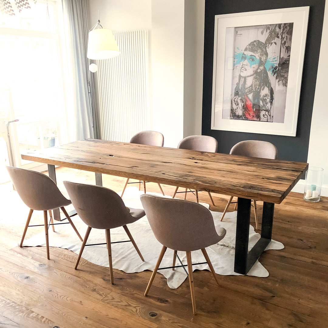 Tisch aus Altholz Eiche mit geschliffener Oberfläche auf zwei Rohstahlframes im Raum und vier Stühlen