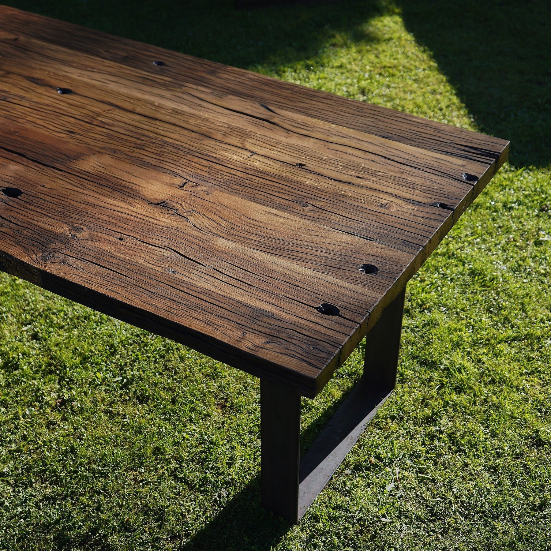 Tisch aus Altholz Eiche mit geschliffener Oberfläche aus Rohstahlframes im Gras